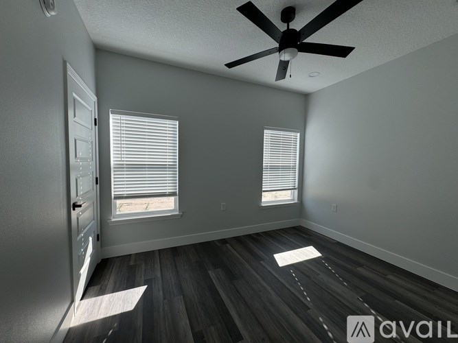 A room with a ceiling fan and two windows.