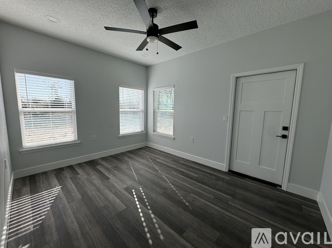 A room with a ceiling fan and wooden flooring.