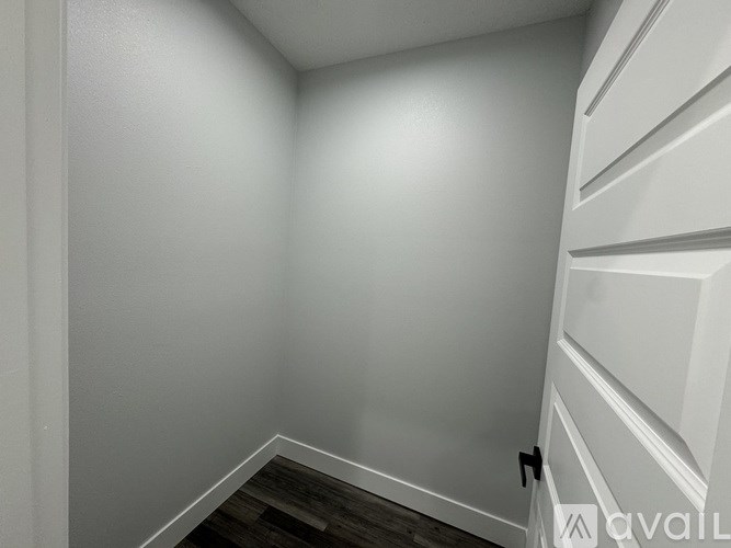 A white hallway with a wooden floor and white walls.