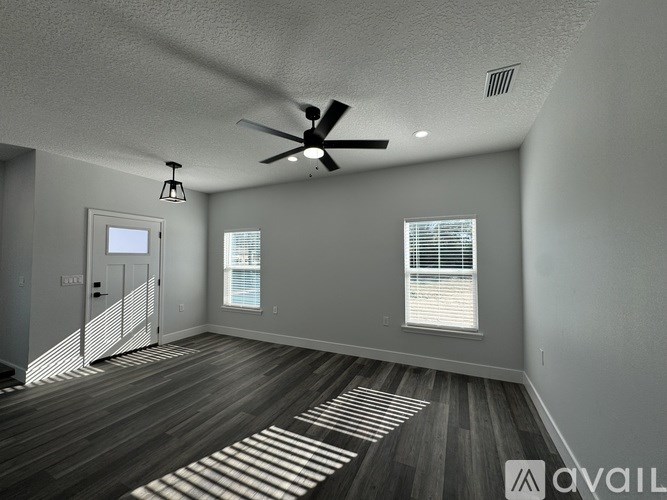 A spacious room with a ceiling fan and wooden flooring.