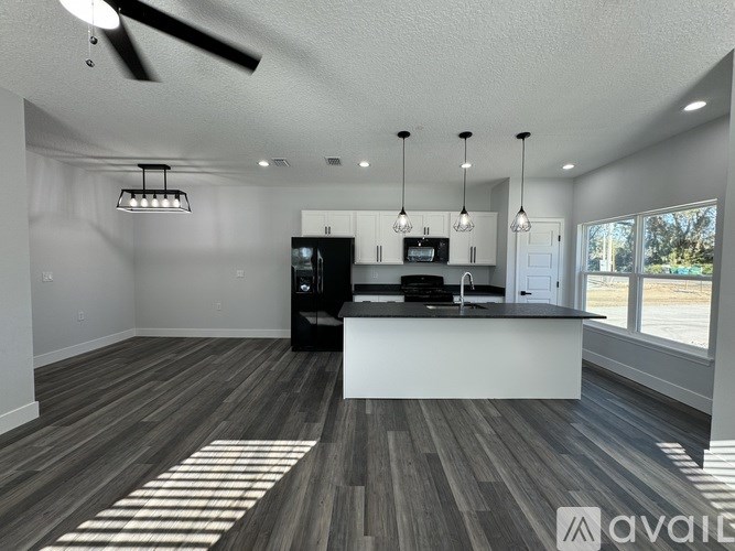 A modern kitchen with a black refrigerator and a ceiling fan.