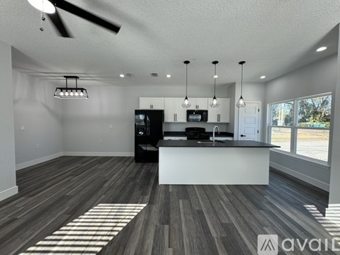 A modern kitchen with a black refrigerator and a ceiling fan.