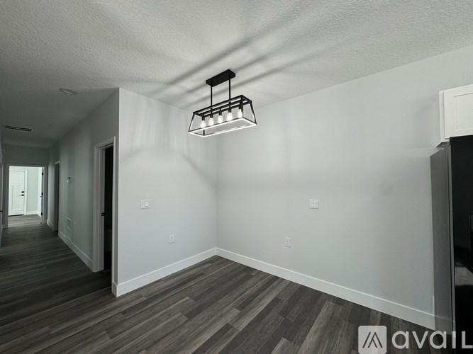 A spacious room with wooden flooring and a track light fixture.
