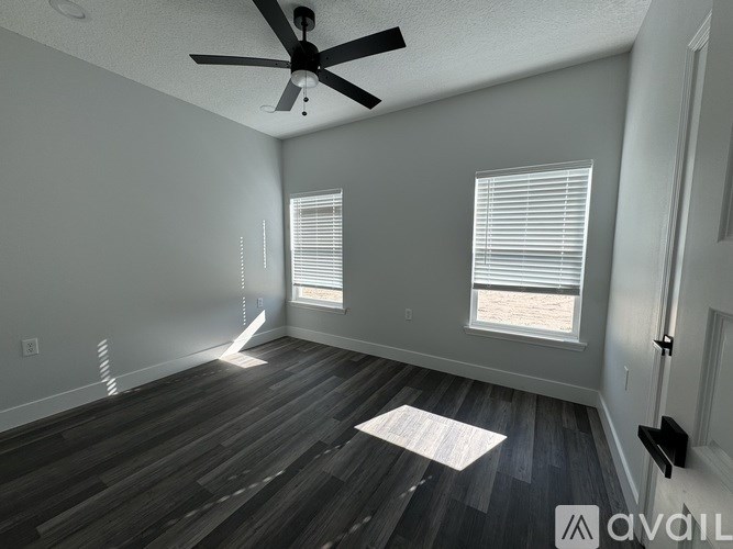 A room with a ceiling fan and two windows.