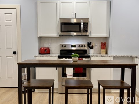 A kitchen with a table and chairs in front of a stove and microwave.