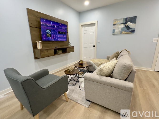 A living room with a grey couch, a black chair, and a wooden entertainment unit.