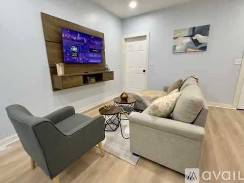 A living room with a grey couch, a black chair, and a wooden entertainment unit.