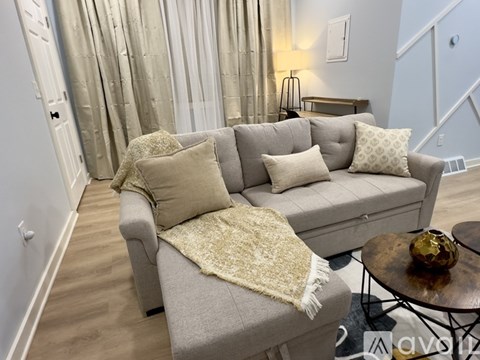 A grey couch with a yellow throw blanket on it.