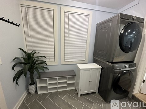 A laundry room with a washer and dryer, a plant, and a bench.