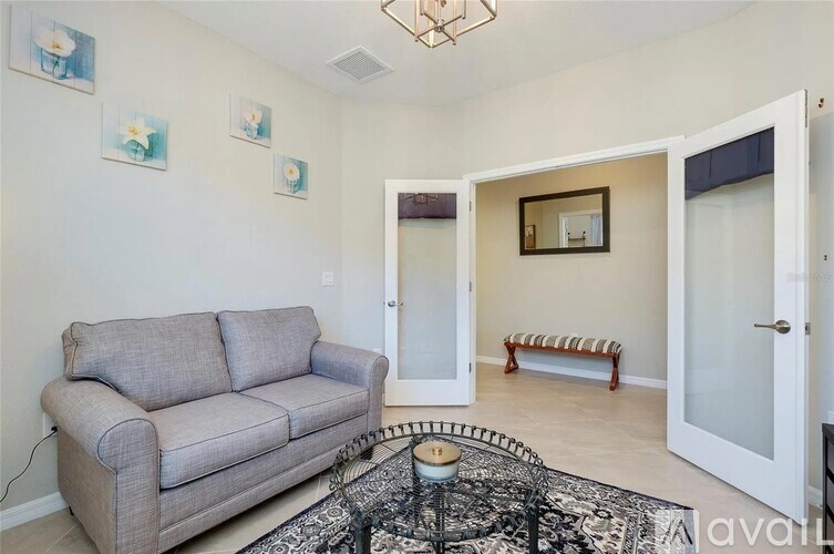 A living room with a grey couch and a black and white patterned rug.