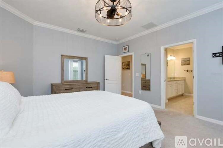 A bedroom with a large bed, a dresser, and a ceiling fan.
