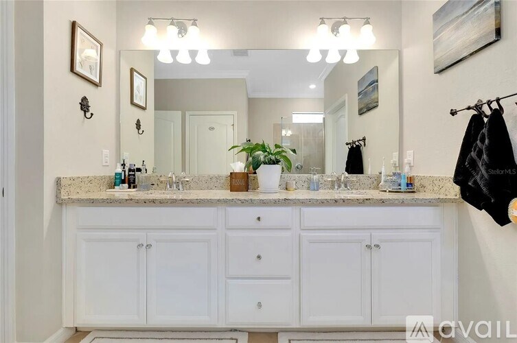 A bathroom with a marble countertop and white cabinets.