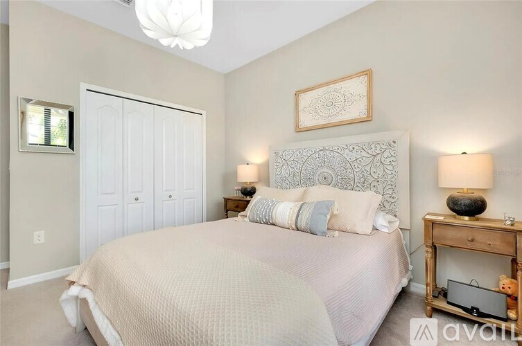A bedroom with a large bed, a wooden nightstand, and a chandelier.