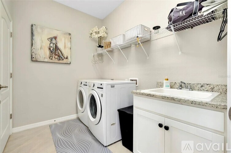 A laundry room with a washer and dryer, a sink, and a painting on the wall.