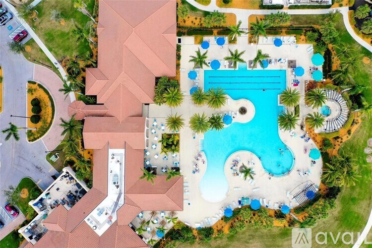 An aerial view of a resort with a large swimming pool and palm trees.