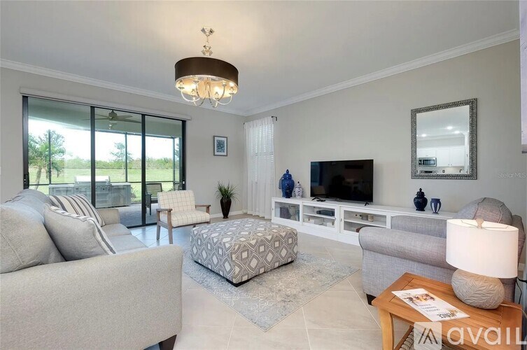 A well-lit living room with a grey couch, a patterned ottoman, and a wooden coffee table.