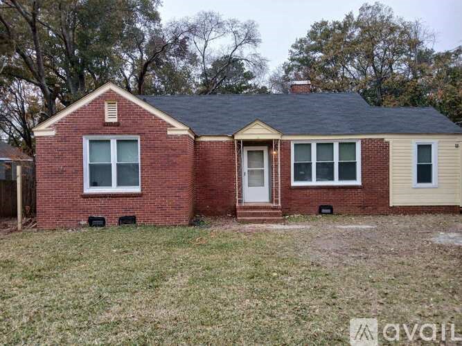 A small red brick house with a white door and windows.