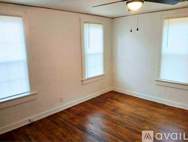 A room with wooden floors and two windows.