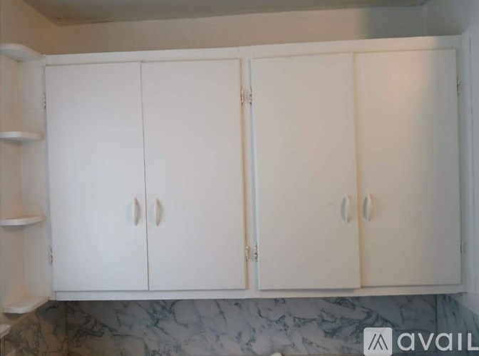 A white cabinet with two doors is in a room.