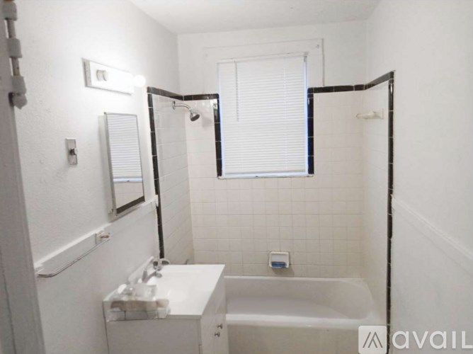 A white bathroom with a sink, mirror, and bathtub.