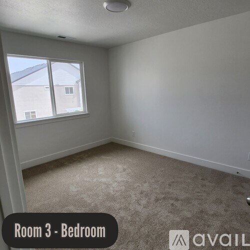 A bedroom with a carpeted floor and a window overlooking a building.