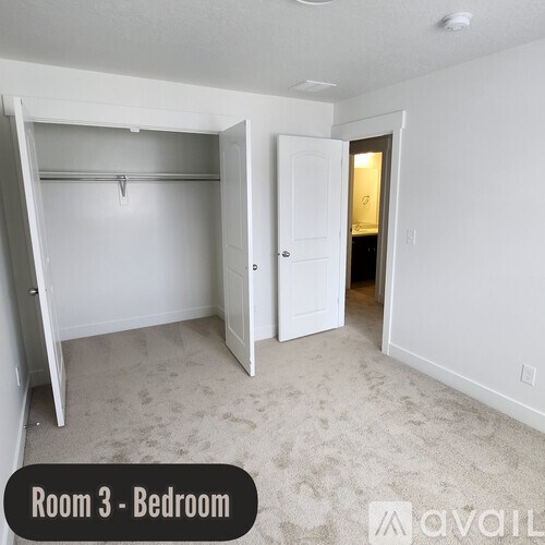 A bedroom with a white door and a white wardrobe.