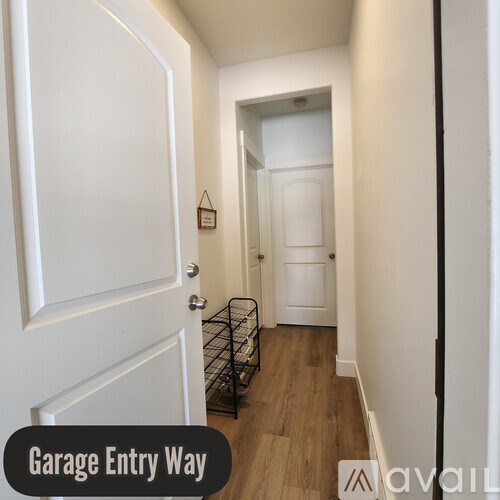 A narrow hallway with a white door and a sign that says Garage Entry Way.