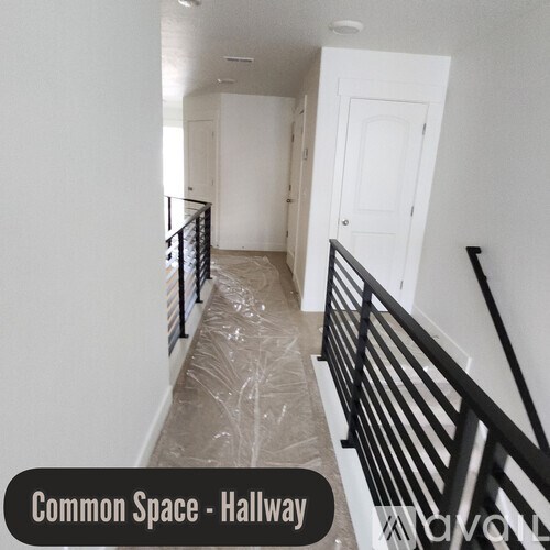 A hallway with a black railing and a white door.