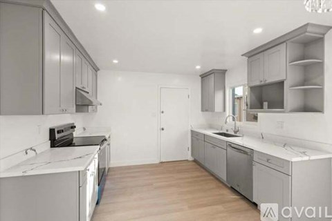 A modern kitchen with grey cabinets and a white countertop.