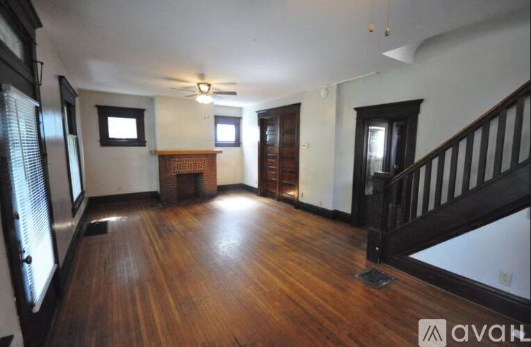 A room with wooden floors and a staircase with a black railing.
