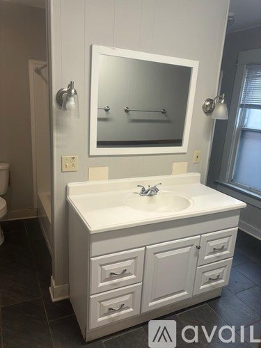 A bathroom with a sink, mirror, and toilet.