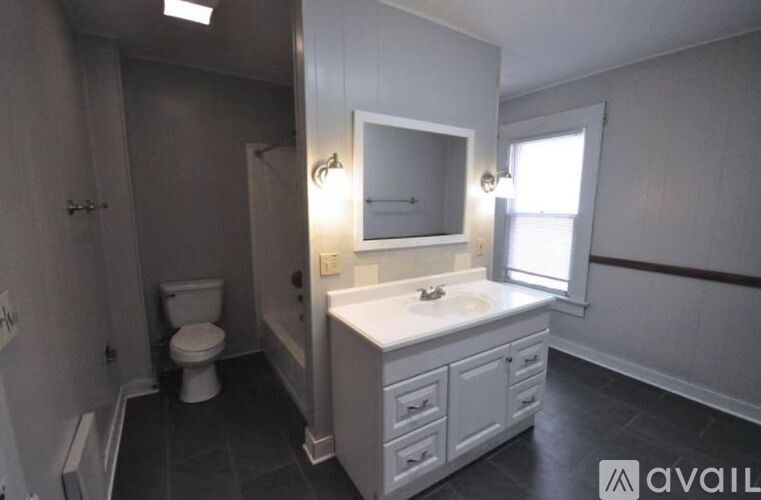 A bathroom with a toilet, sink, and mirror.