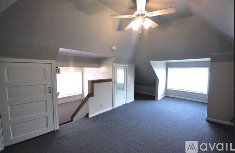 A room with a ceiling fan and a carpeted floor.
