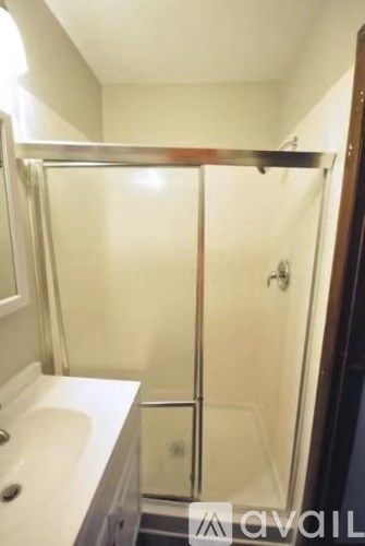 A bathroom with a glass shower door and a white sink.