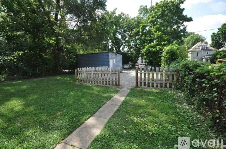 A backyard with a wooden fence and a concrete walkway.