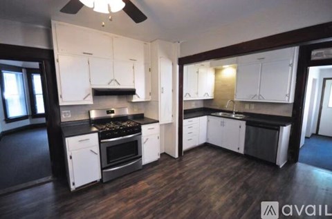 A kitchen with white cabinets and black countertops.