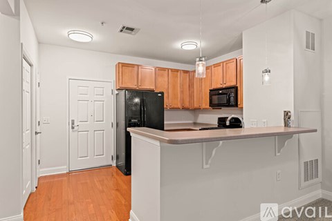 A kitchen with wooden cabinets and a black refrigerator.