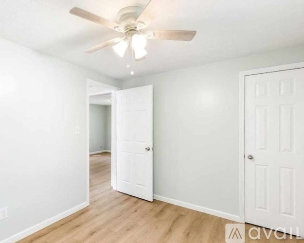 A room with a ceiling fan and two doors.