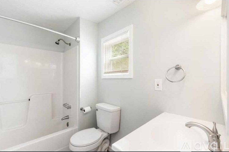 A white bathroom with a toilet, sink, and bathtub.