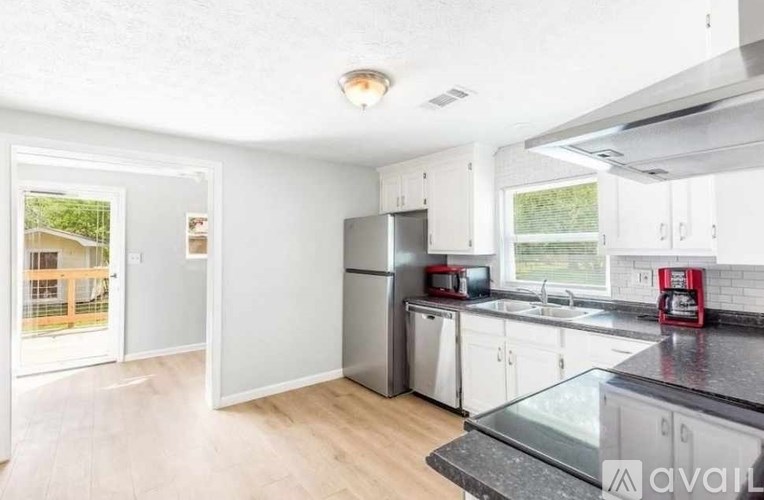 A kitchen with white cabinets and a black countertop.