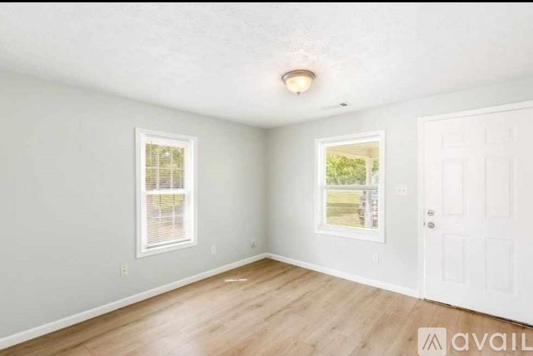 A room with a white door and a window with a view of a garden outside.