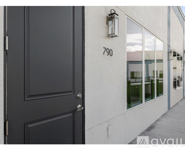 A black door with a silver handle and a number 790 on the wall.
