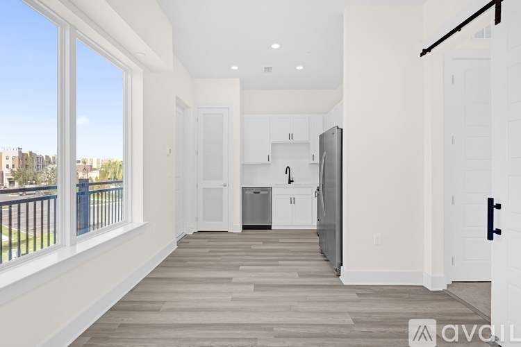 A spacious, empty room with a kitchen area in the background.