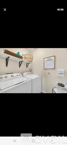 A laundry room with a washer and dryer, a basket on the shelf, and a calendar on the wall.