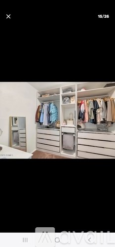 A white closet with clothes hanging and drawers underneath.