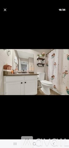 A white bathroom with a toilet, sink, and a shower curtain with a pattern of people on it.