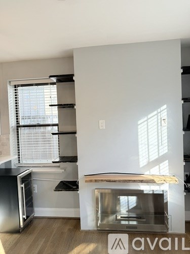 A kitchen with a stainless steel refrigerator and a window with blinds.