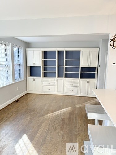 A kitchen with white cabinets and a wooden floor.