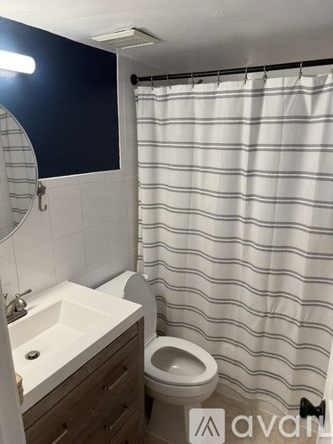 A bathroom with a toilet, sink, and shower curtain.
