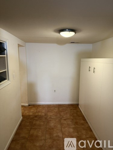 A room with a brown tile floor and white walls.